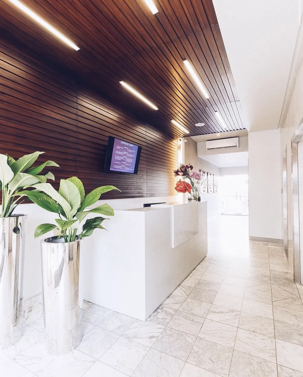 Lobby del edificio In Tempo con recepción, techo de madera y piso de mármol